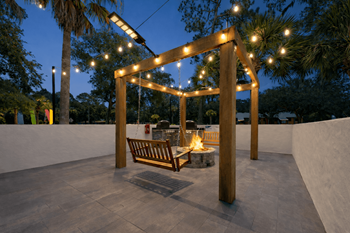 A wooden pergola with lights and a bench in the middle of a patio.